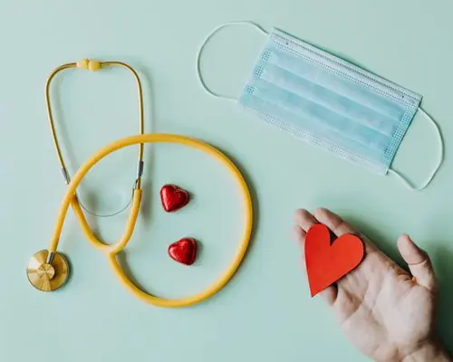 Stethoscope, face mask and red hearts on a mint background