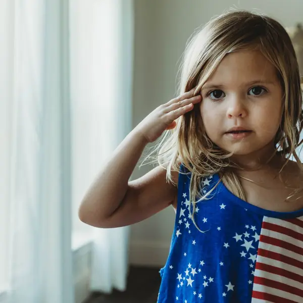 Young girl in a stars-and-stripes dress saluting
