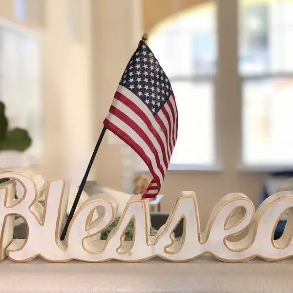 Small American flag beside a wooden “Blessed” sign