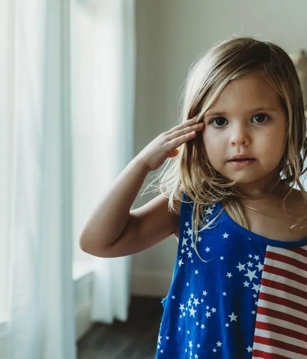 Young girl in a stars-and-stripes dress saluting